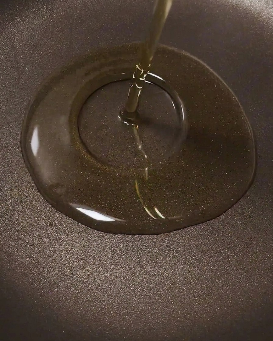 A raw, marinated chicken leg being laid flat into a hot frying pan.