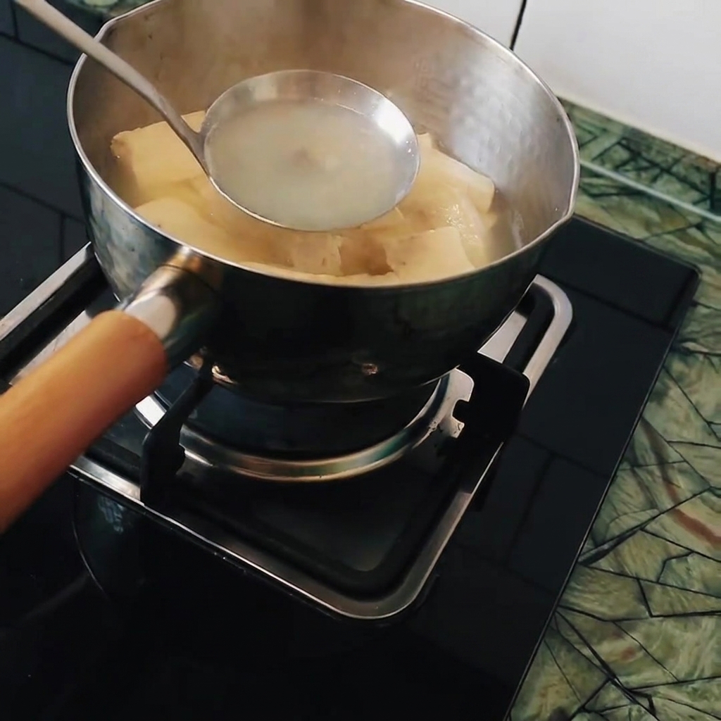 A ladle stirring a pot of hot water and tofu, preparing to dissolve the Japanese curry blocks.