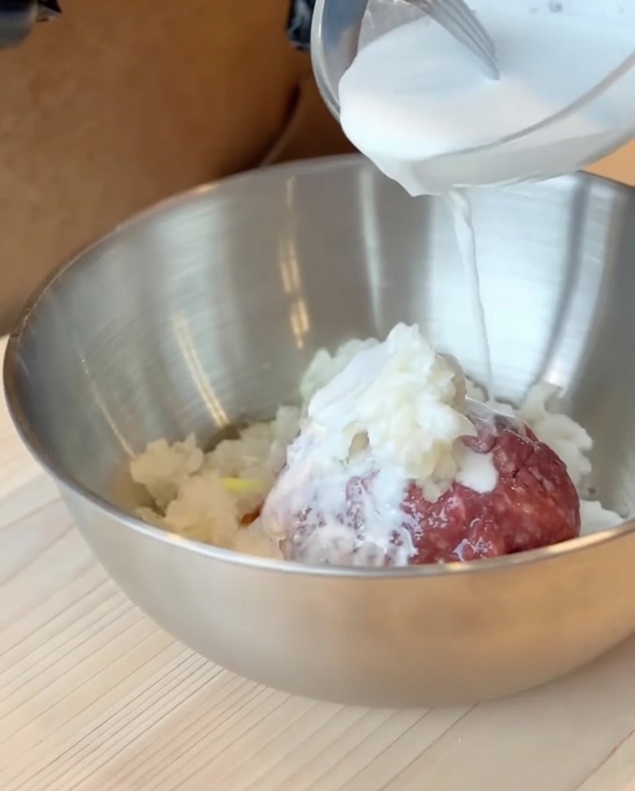 The milk and sweet potato flour batter being poured over the ground beef mixture in a large bowl.