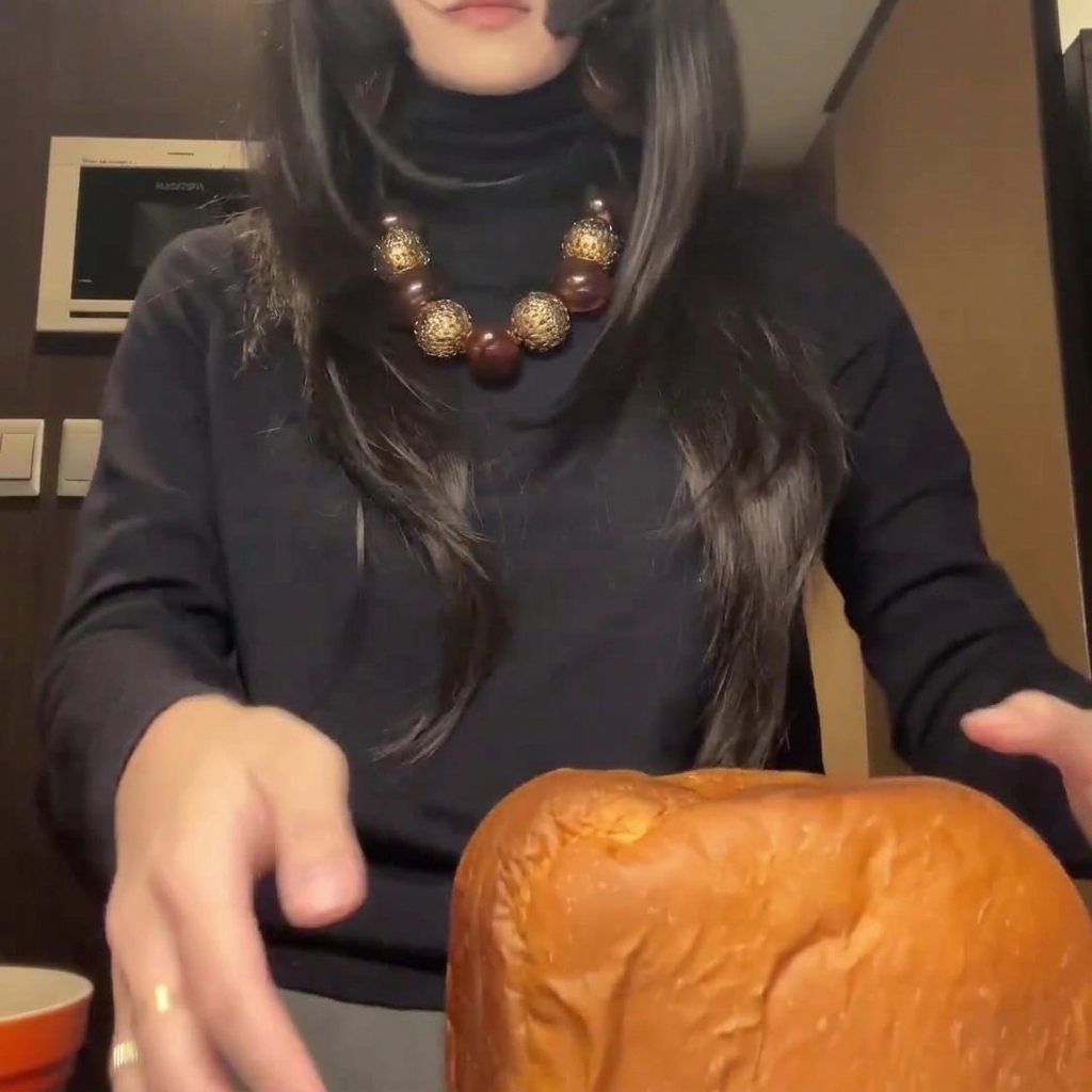 Freshly baked, golden-brown loaf of bread being sliced into thick, uniform pieces on a cutting board.