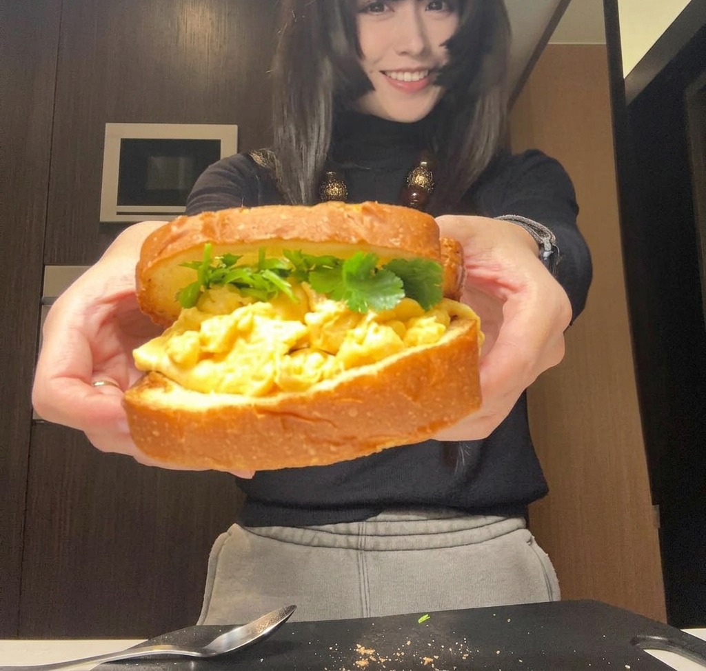 A fully assembled sandwich held in two hands, ready to be wrapped or sliced.