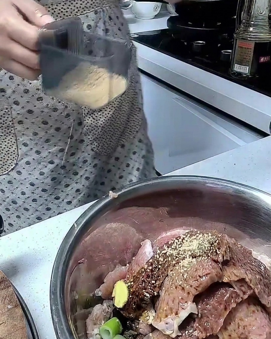 Ingredients being mixed with raw pork slices in a stainless steel mixing bowl.