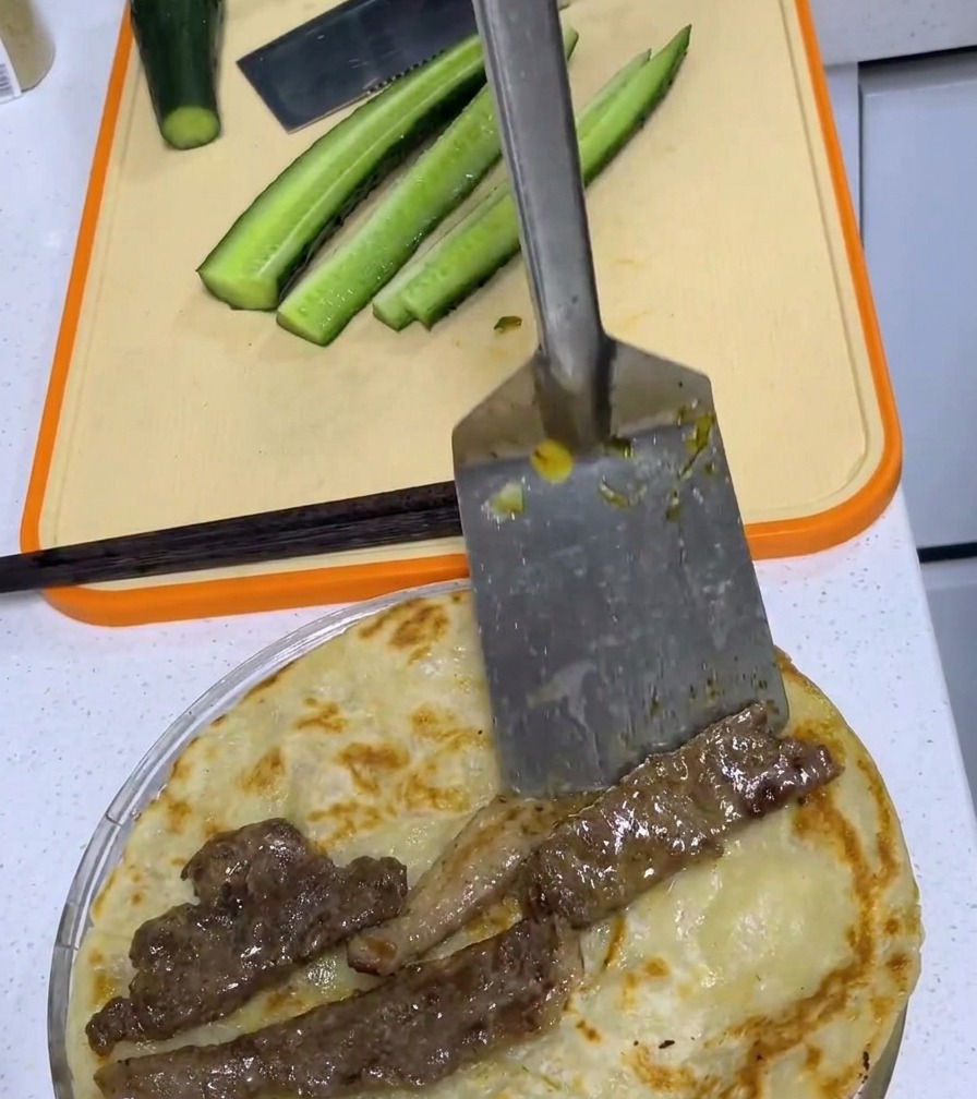A pan-fried pork chop centered on a golden-brown scallion pancake on a cutting board.