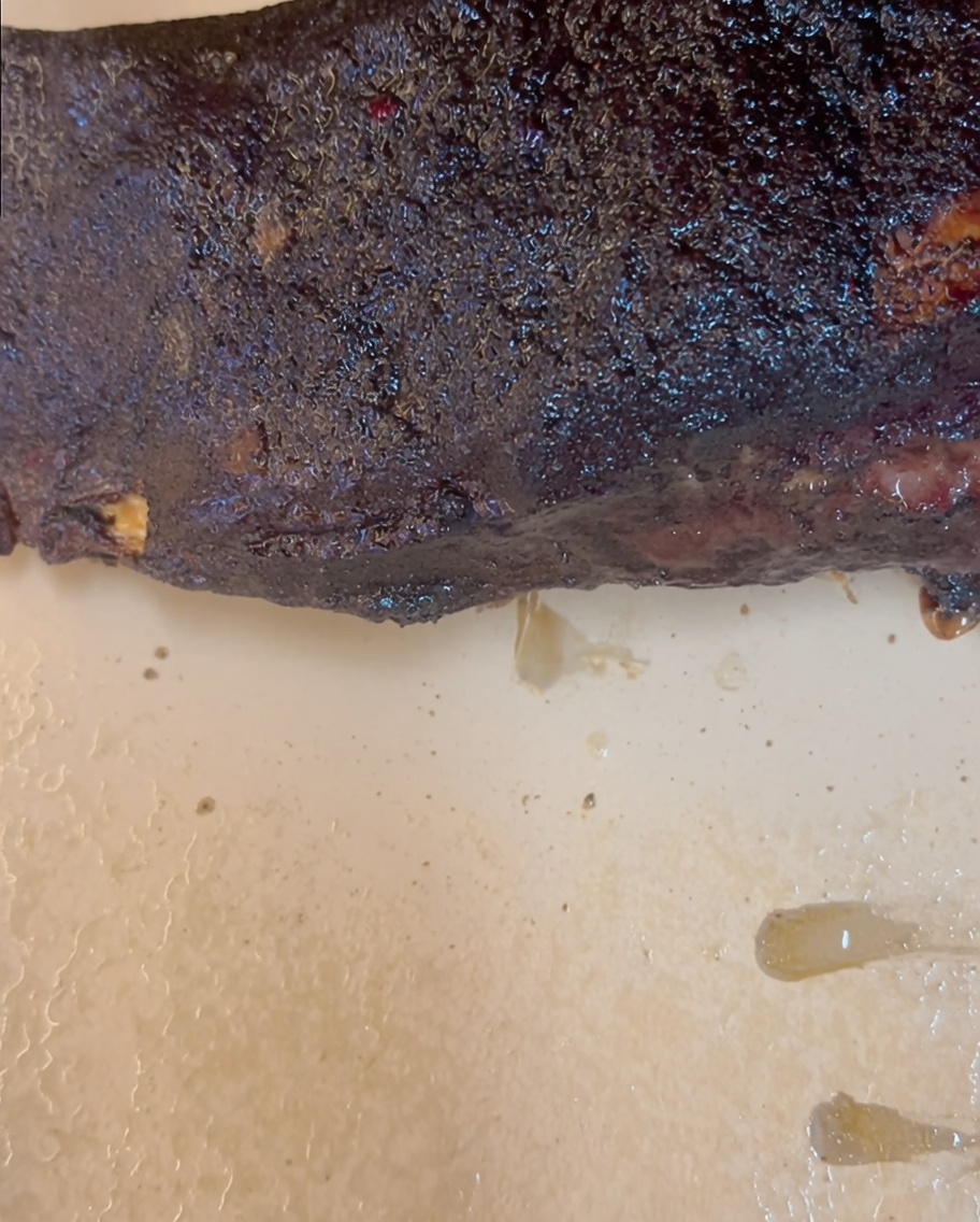 The side edge of the butcher paper being folded inward over the end of a beef rib.