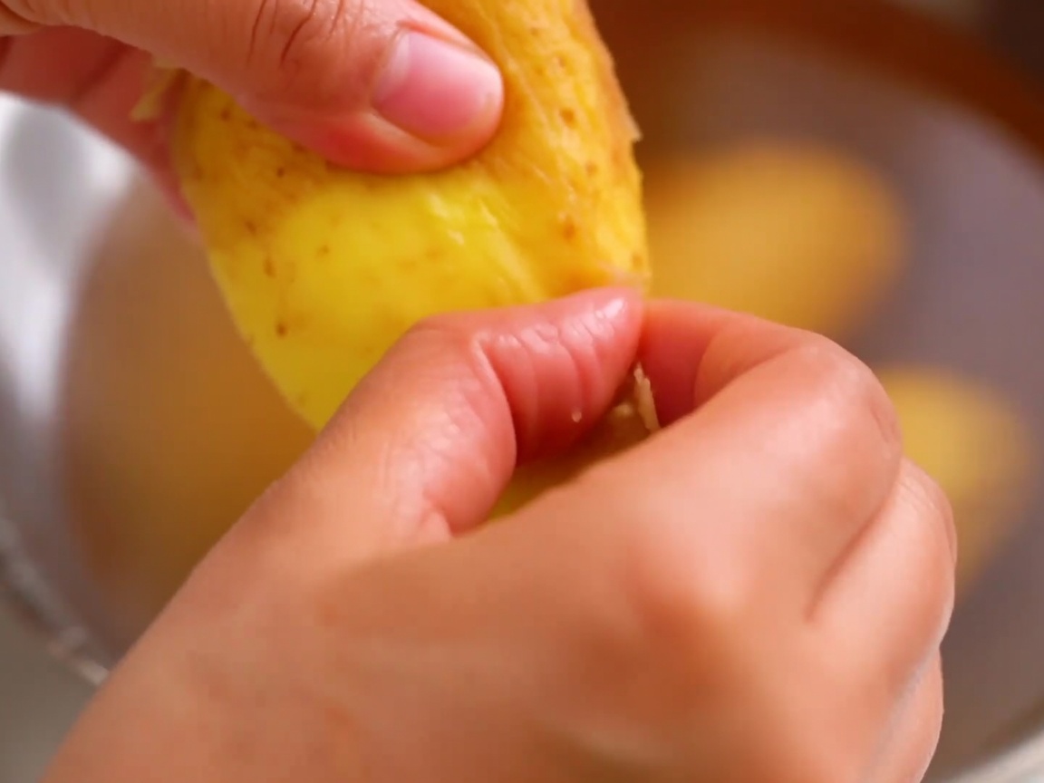 Peeling the skin off a thawed potato with fingers.