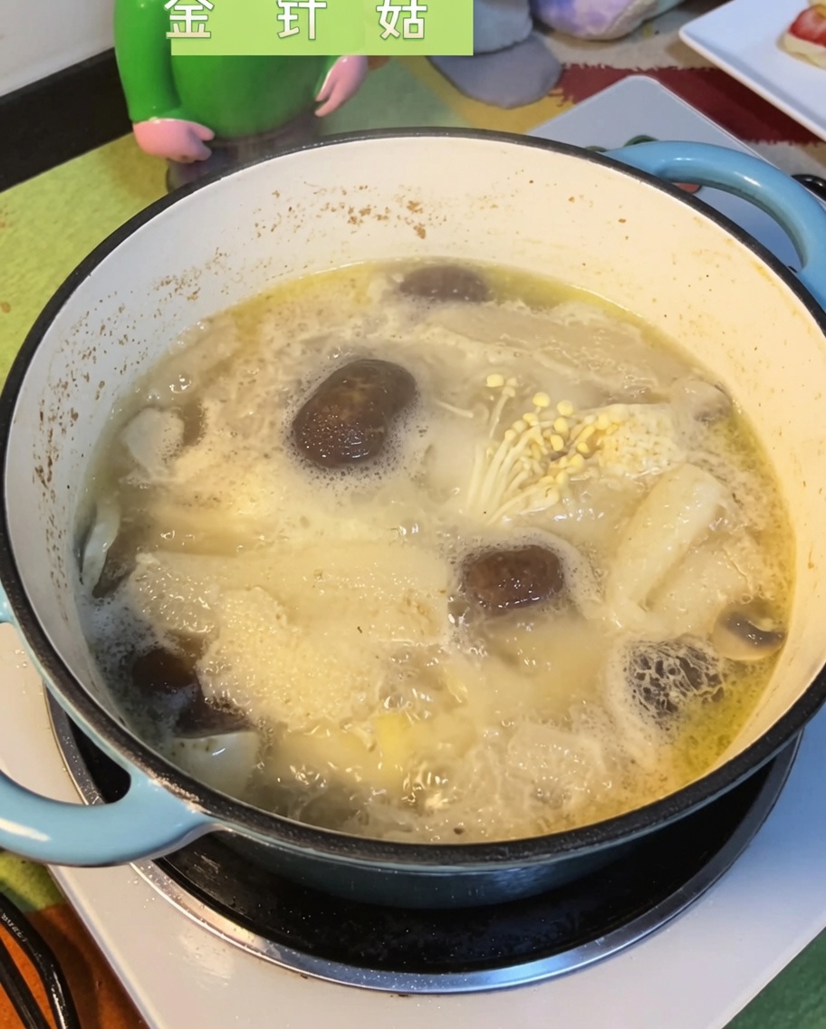 Enoki mushrooms being submerged into the bubbling, flavorful mushroom and chicken broth.