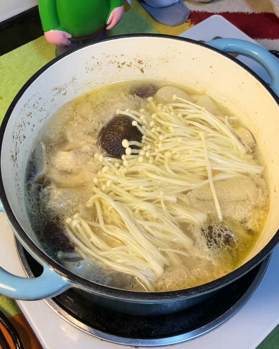 Yellow noodles softening as they are added into the pot of chicken and mushroom soup.