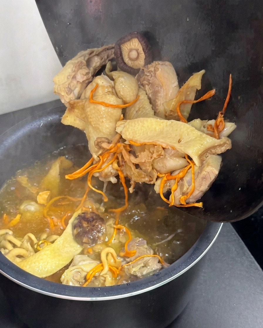 Chicken and mushroom broth being transferred into an electric rice cooker pot.