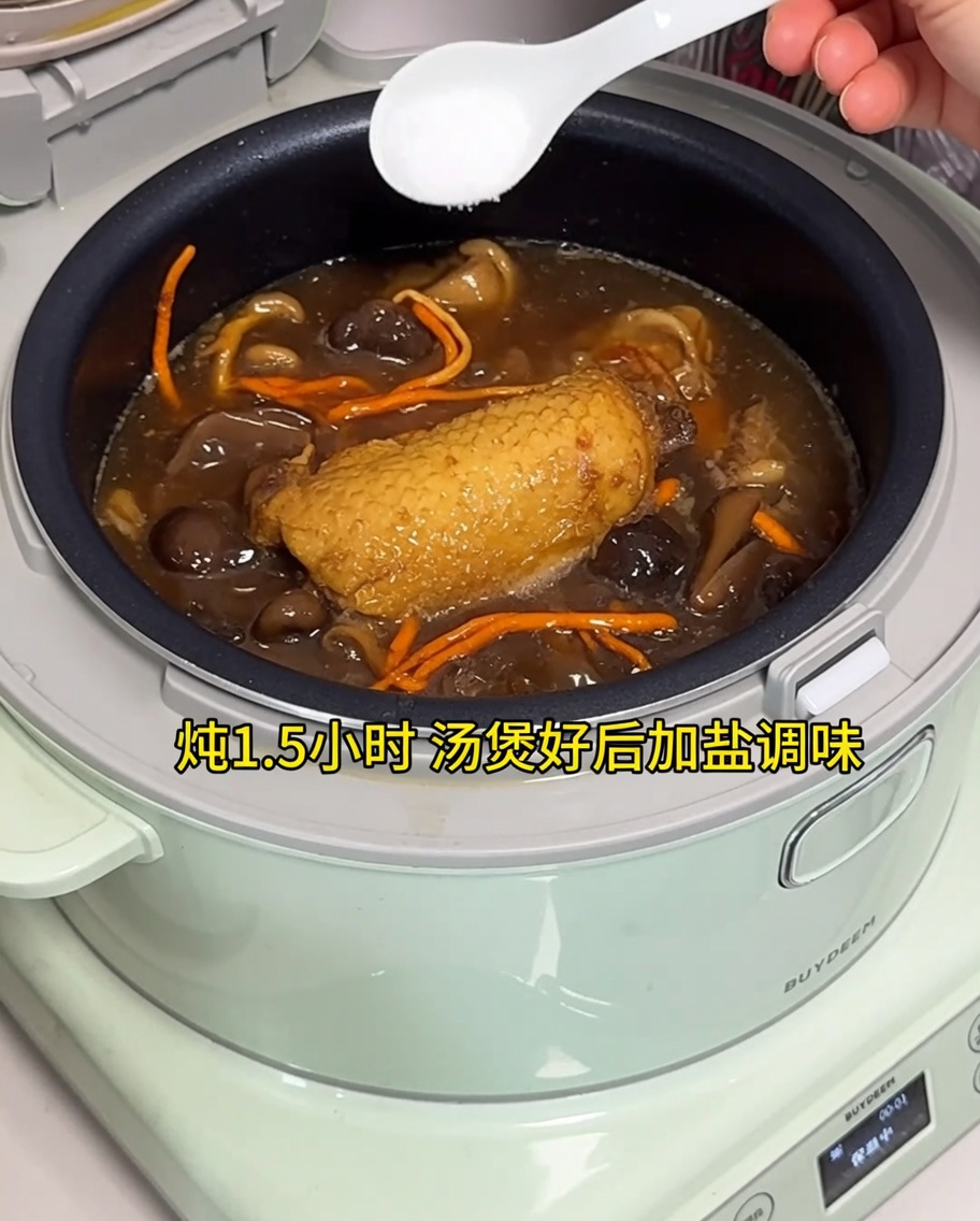 Adding salt to the finished chicken soup in an electric rice cooker.