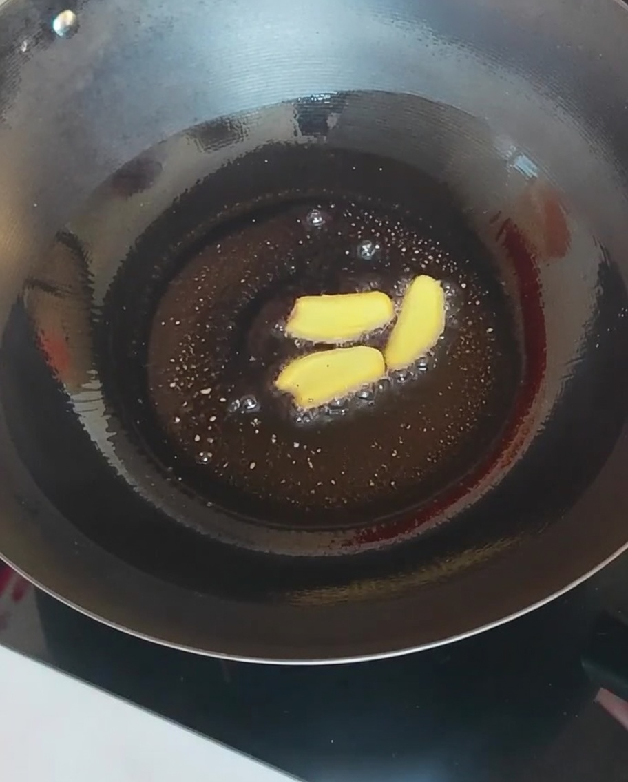 Ginger slices and various mushrooms being stir-fried in a hot wok.