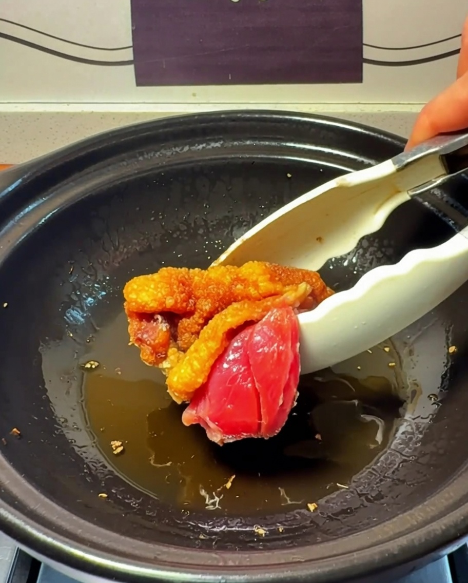 Chicken pieces searing and browning in the clay pot.