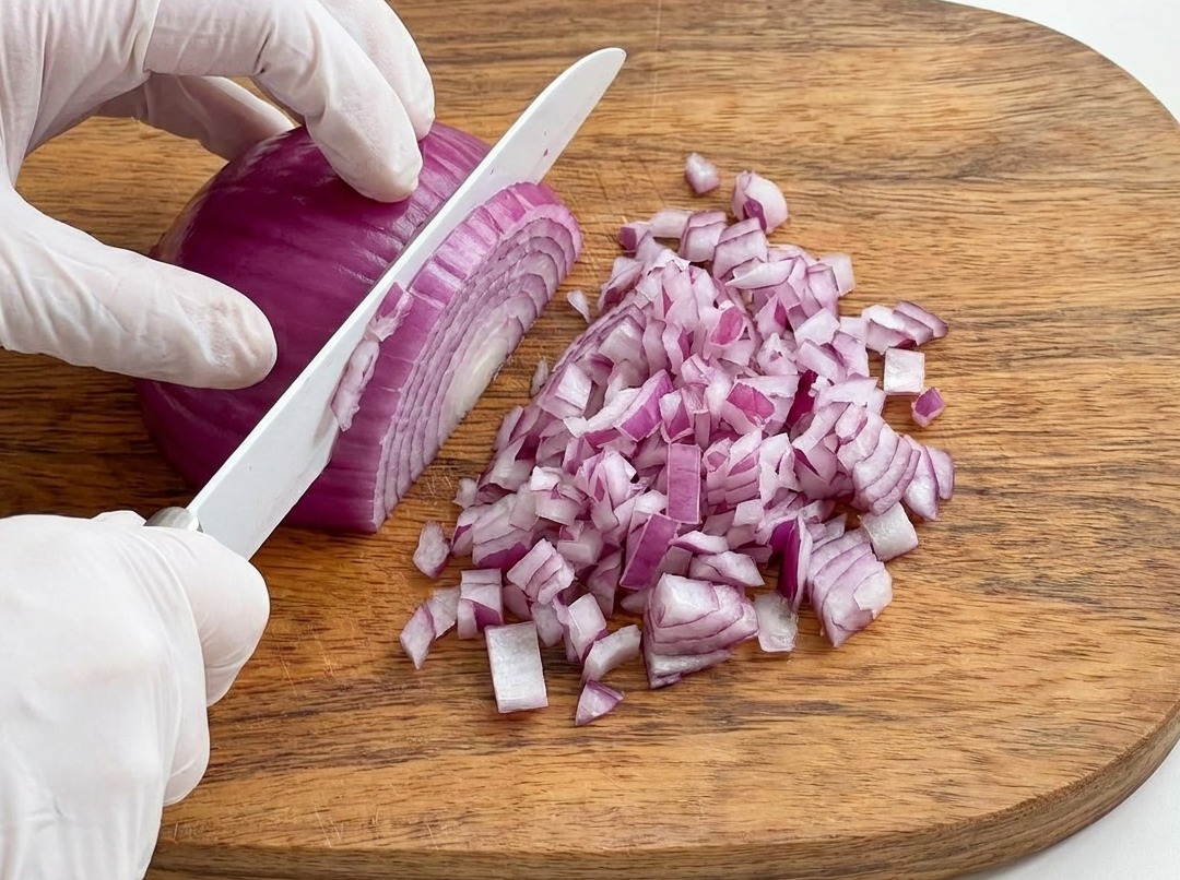 Red onion being finely diced on a wooden board.
