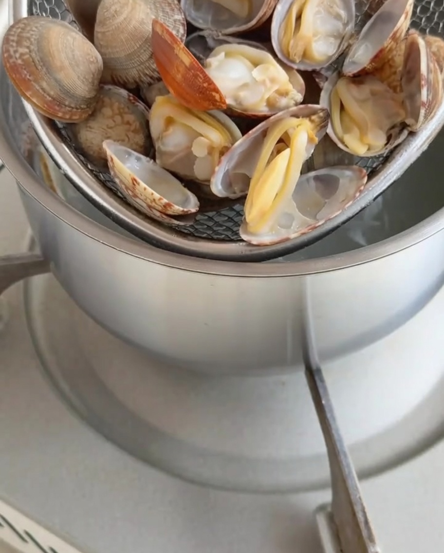 Cooked clam meat being removed from the shells.