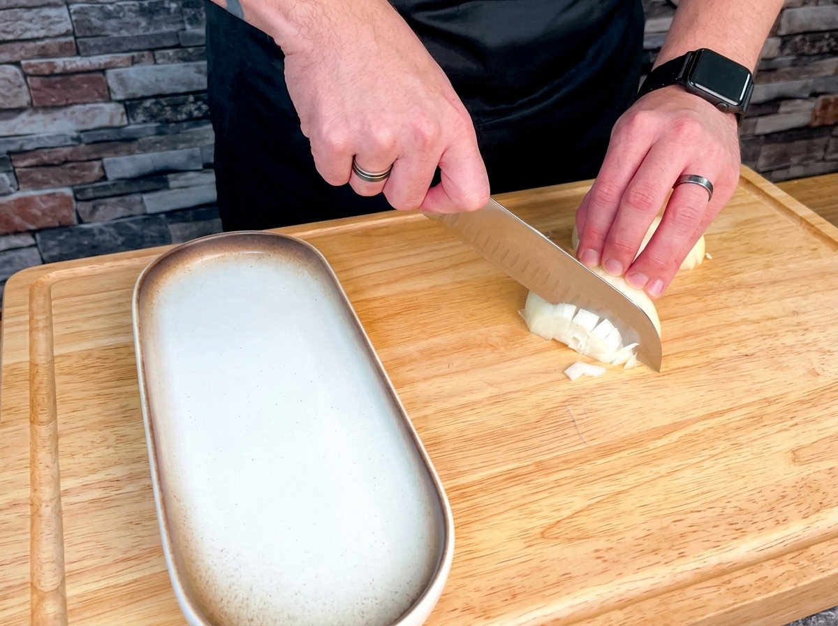 A variety of fresh vegetables including onions, celery, carrots, garlic, and potatoes neatly diced on a large wooden cutting board.