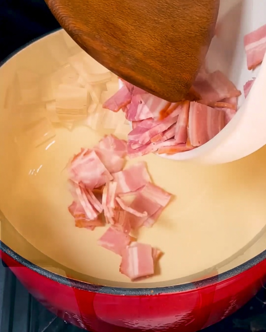 Crispy golden-brown bacon pieces sizzling in a vibrant red Dutch oven.