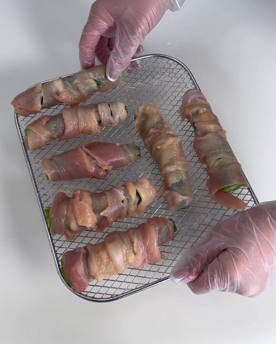 Several okra chicken wraps laid out on a metal wire drying rack.