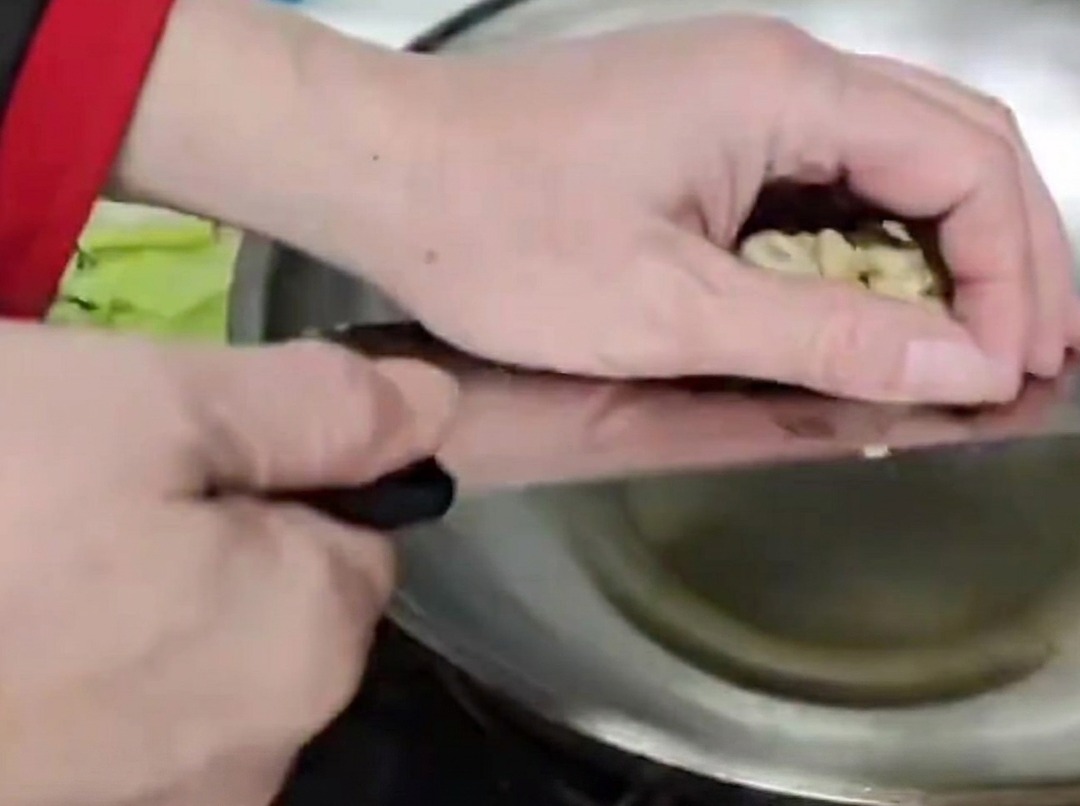 Bamboo shoot stems being stir-fried in a hot metal wok with oil.