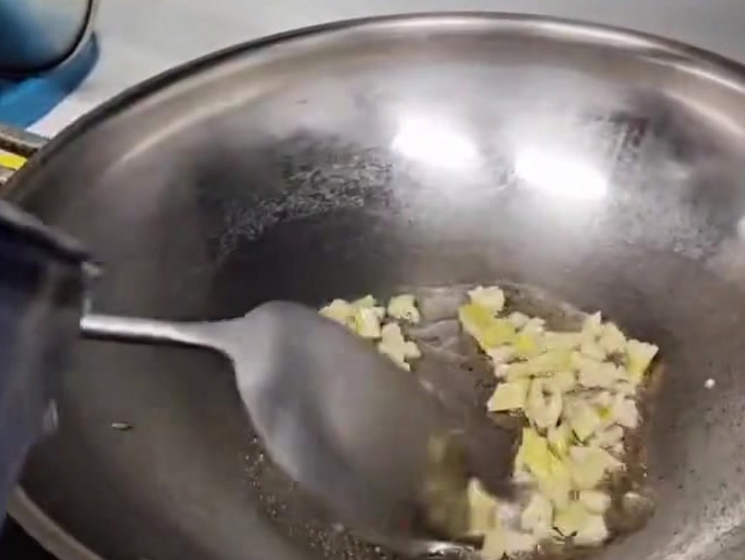 Water being poured into a metal wok to form the mushroom soup base.