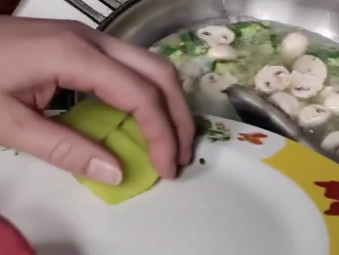 Slices of bamboo shoots being added to the mixture of meatballs, mushrooms, and okra in the wok.