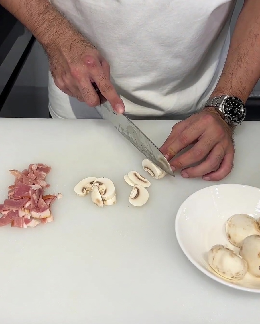 Fresh mushrooms being sliced into thick, uniform pieces.