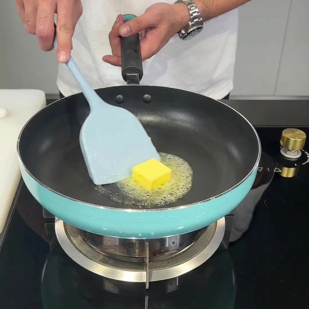 A knob of butter melting in a skillet with minced garlic added.