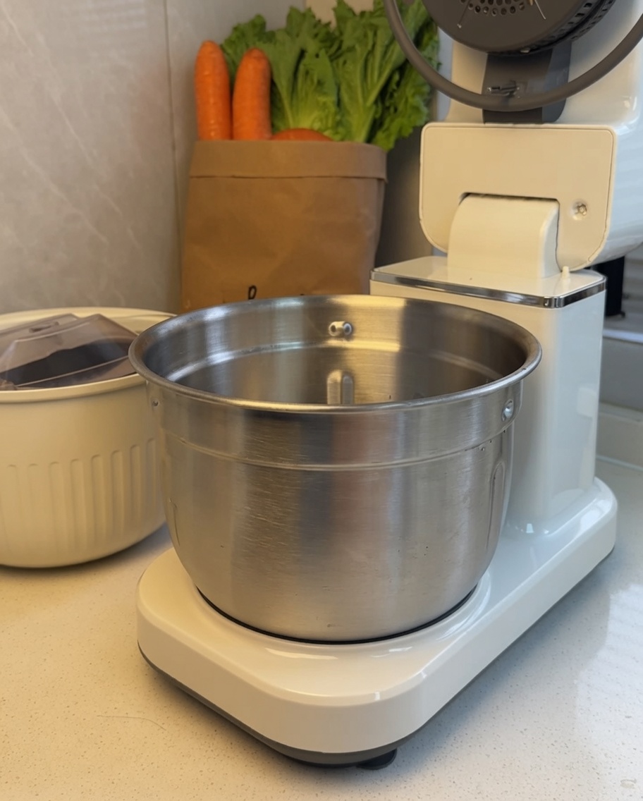 Beef chunks inside the stainless steel mixing bowl of a stand mixer.
