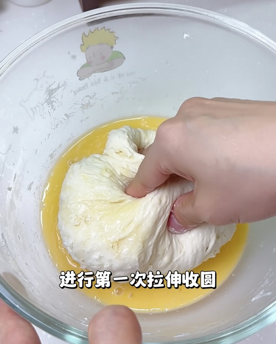 Hands stretching and folding pizza dough inside a bowl to develop its texture.