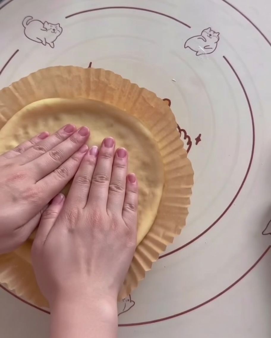 Dough being shaped into an air fryer liner with hands creating a raised edge.