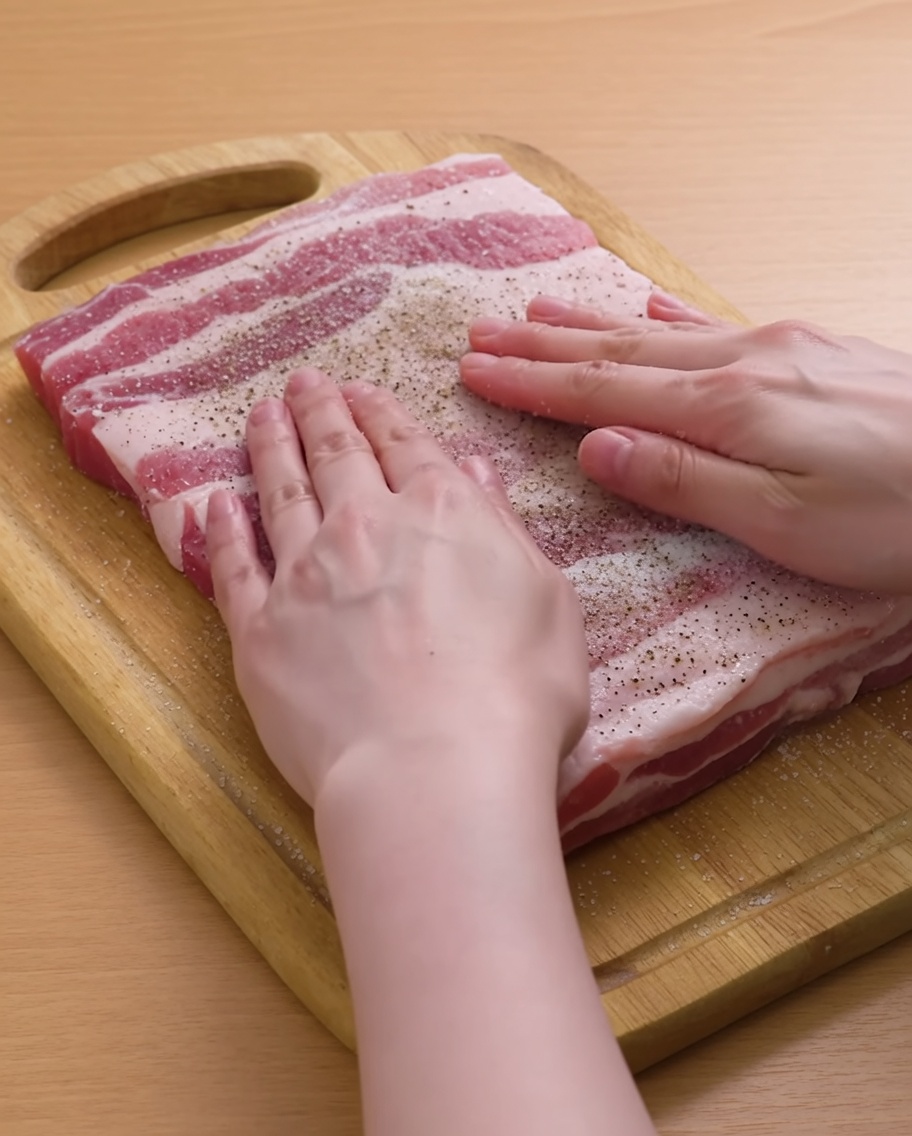 Two tightly rolled pork belly cylinders held together with wooden toothpicks.