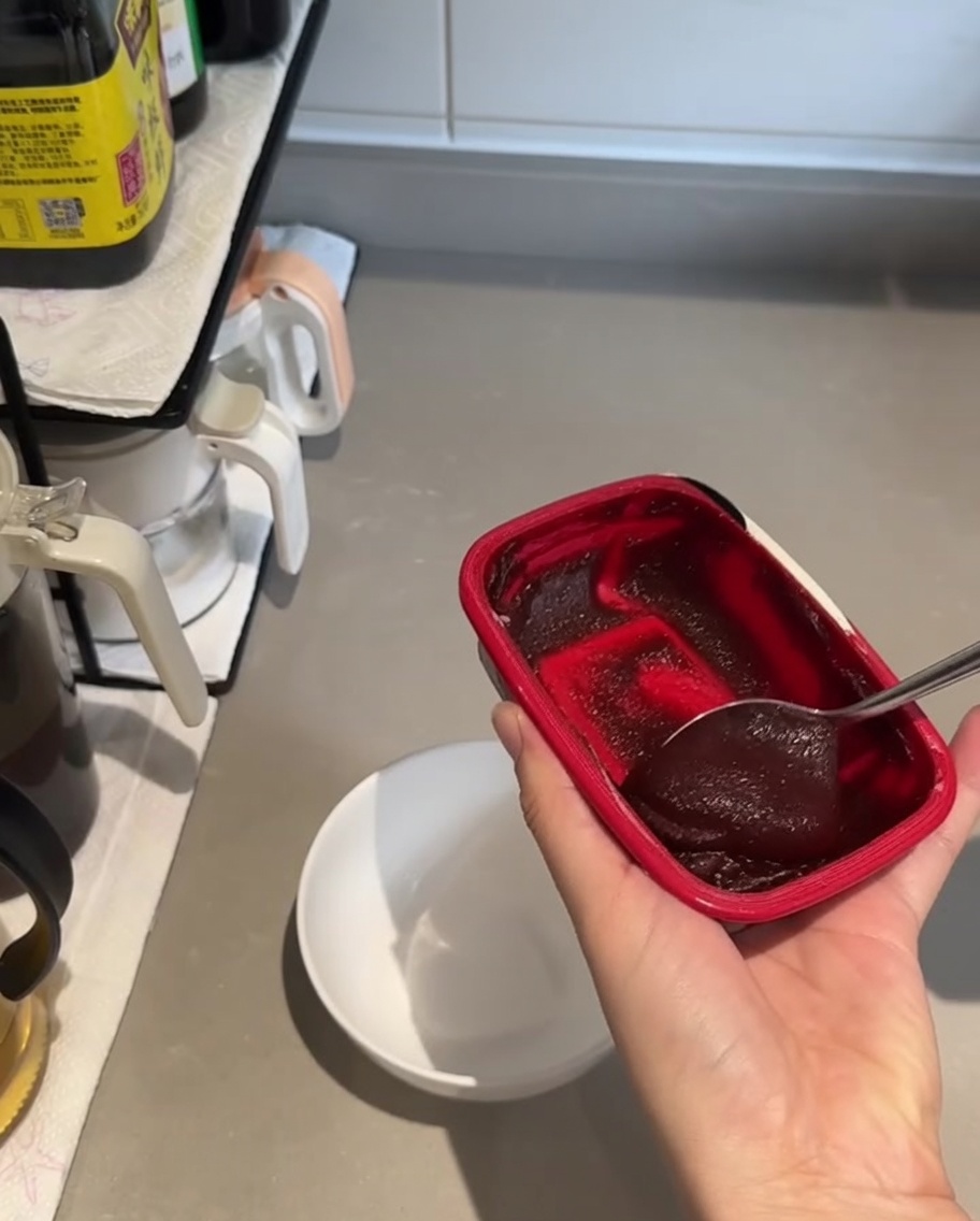 A small white bowl containing a large spoonful of dark red gochujang paste and soy sauce, ready to be mixed.