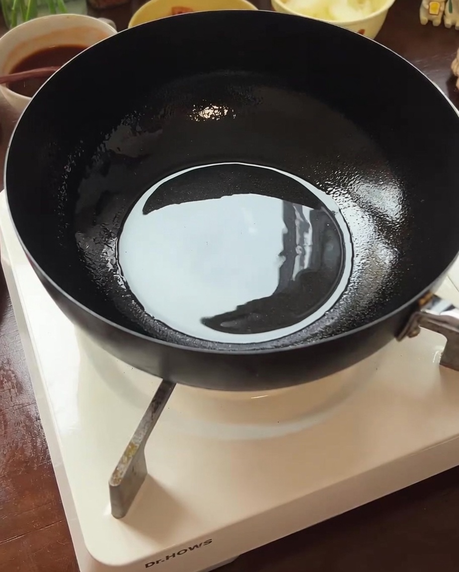 Fresh beef slices being seared in a hot pan with oil until browned.