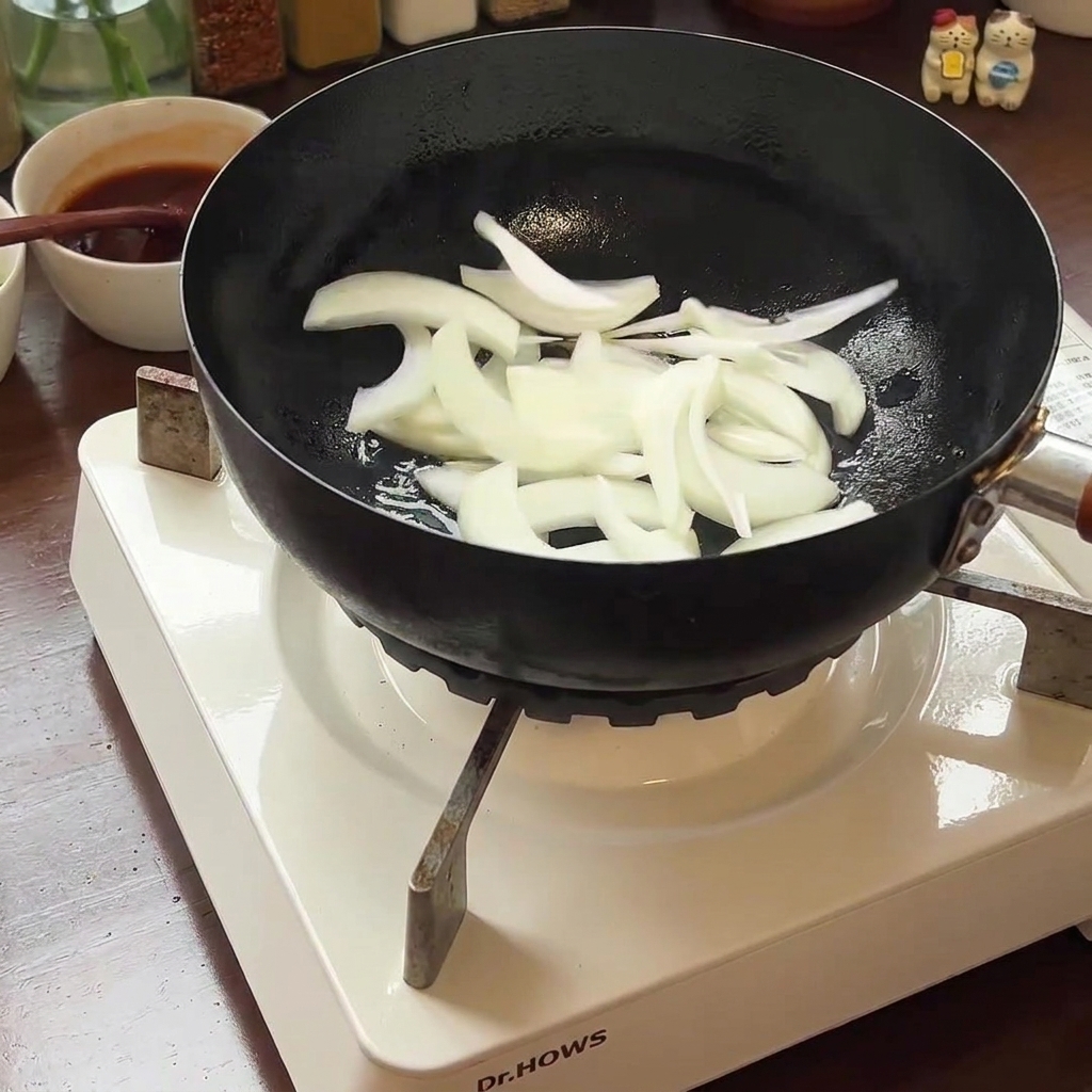 Sliced onions and kimchi cooking in the pan, softening over heat.