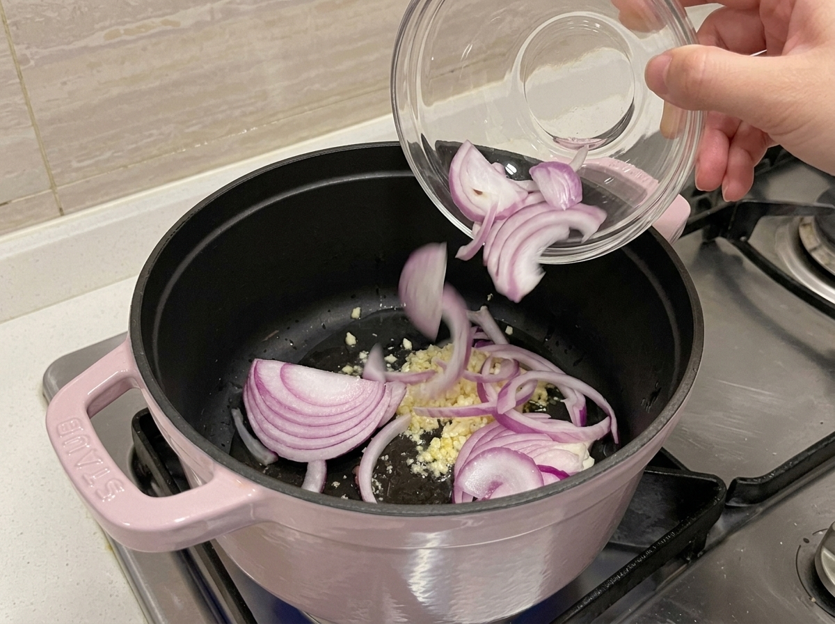 Minced garlic and sliced red onion sautéing in a pot with oil.