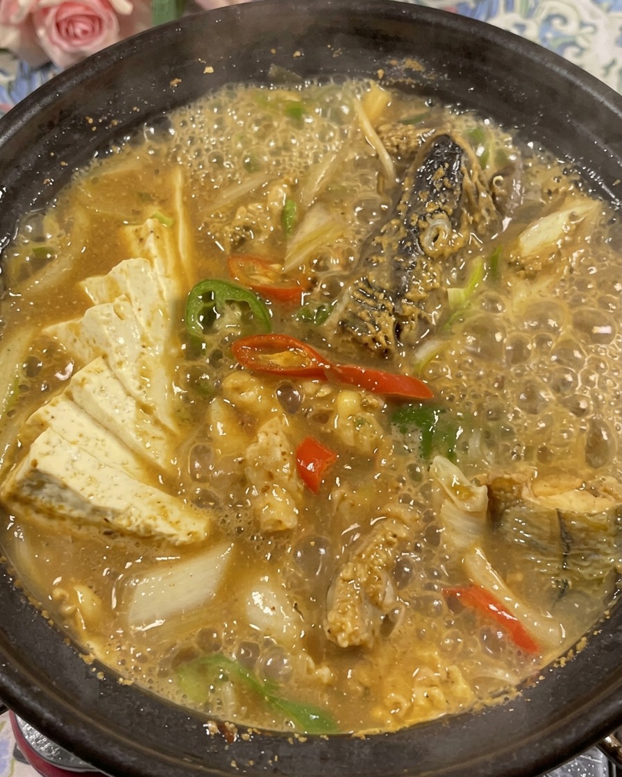 The finished pollack and soybean paste stew garnished with fresh green cilantro in the clay pot.