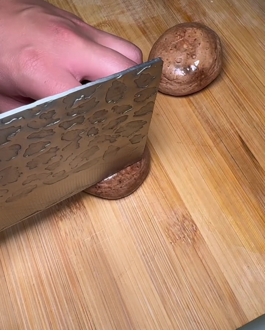 Freshly sliced raw shiitake mushrooms piled on a wooden cutting board.