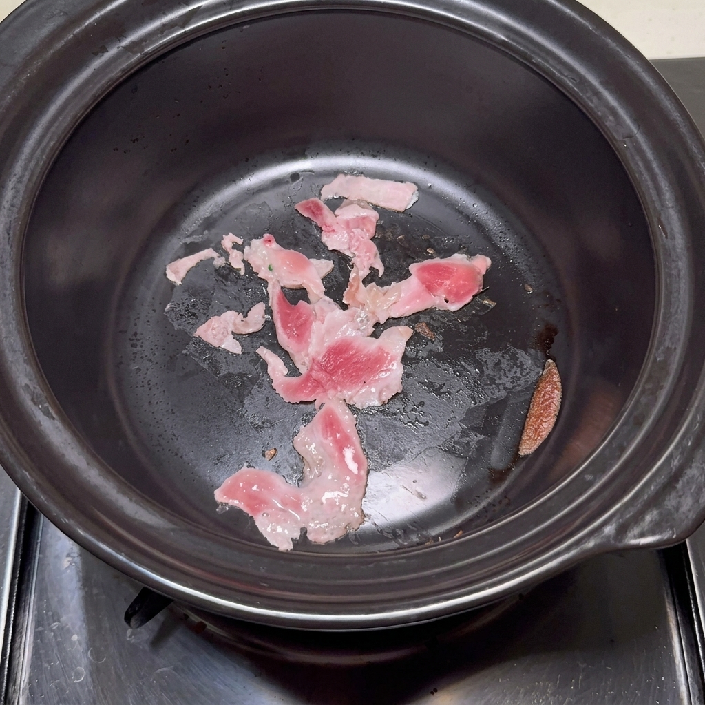 Clear water being poured from a ladle into a stone pot containing lightly seared pork.