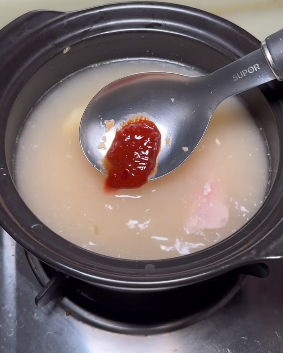 Fresh soybean sprouts being pushed into the broth using a metal blade.