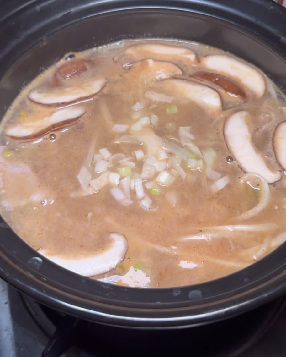 Korean chili powder and seasonings being sprinkled into the flavorful soybean paste stew.