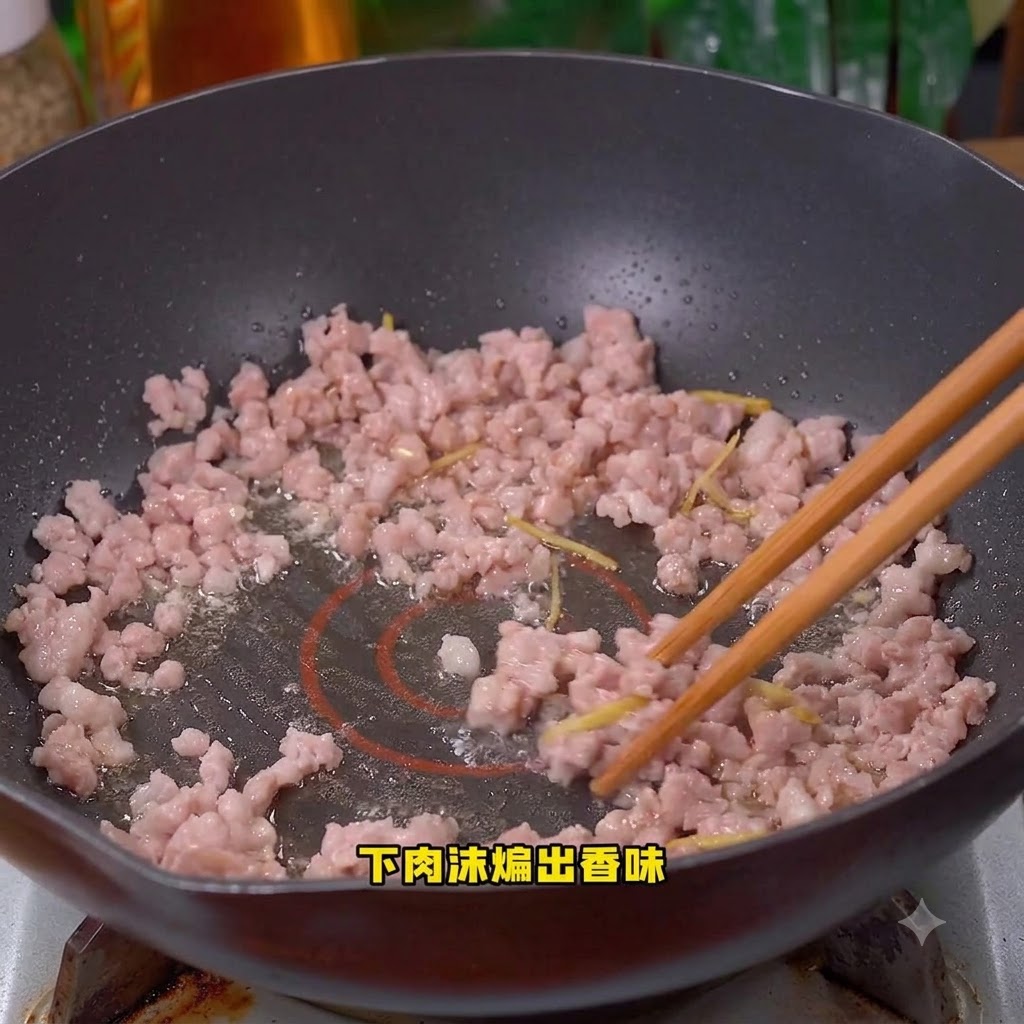 Minced pork being cooked and stirred in the wok.