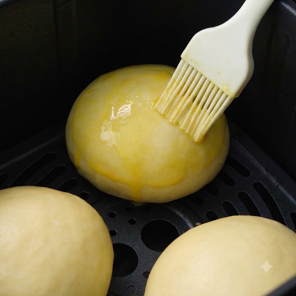 White sesame seeds being sprinkled onto the top of shaped buns.