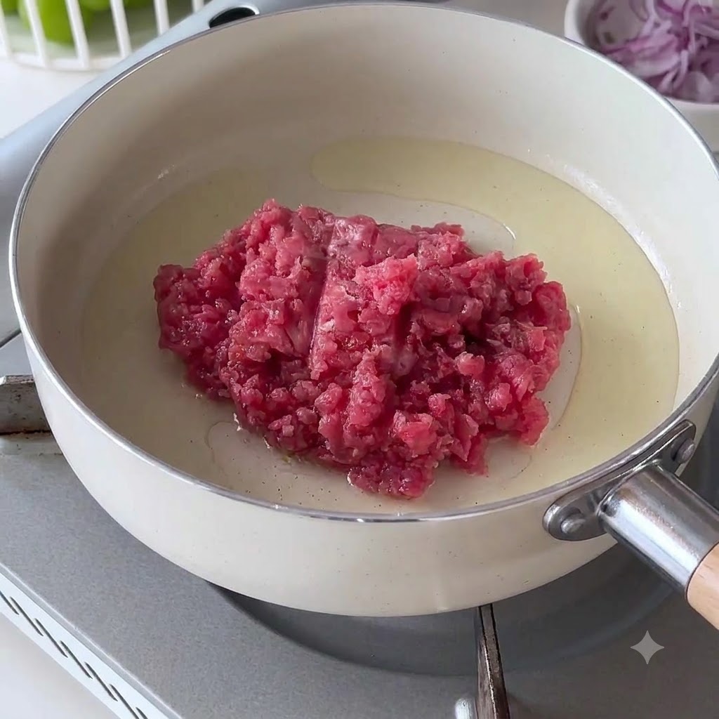Raw minced beef placed into a hot white pan with oil.