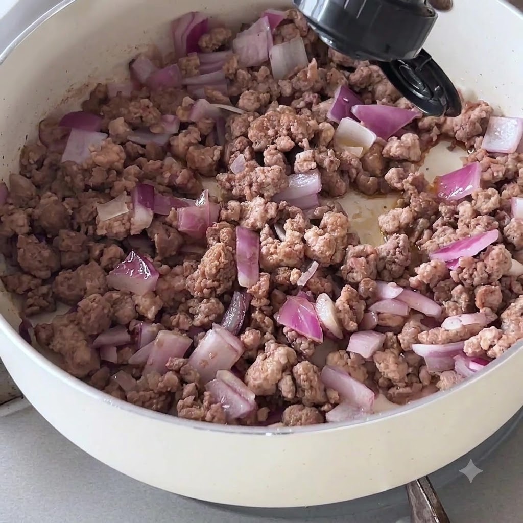 Dark sauce being poured from a bottle onto cooked minced beef and onions in a pan.