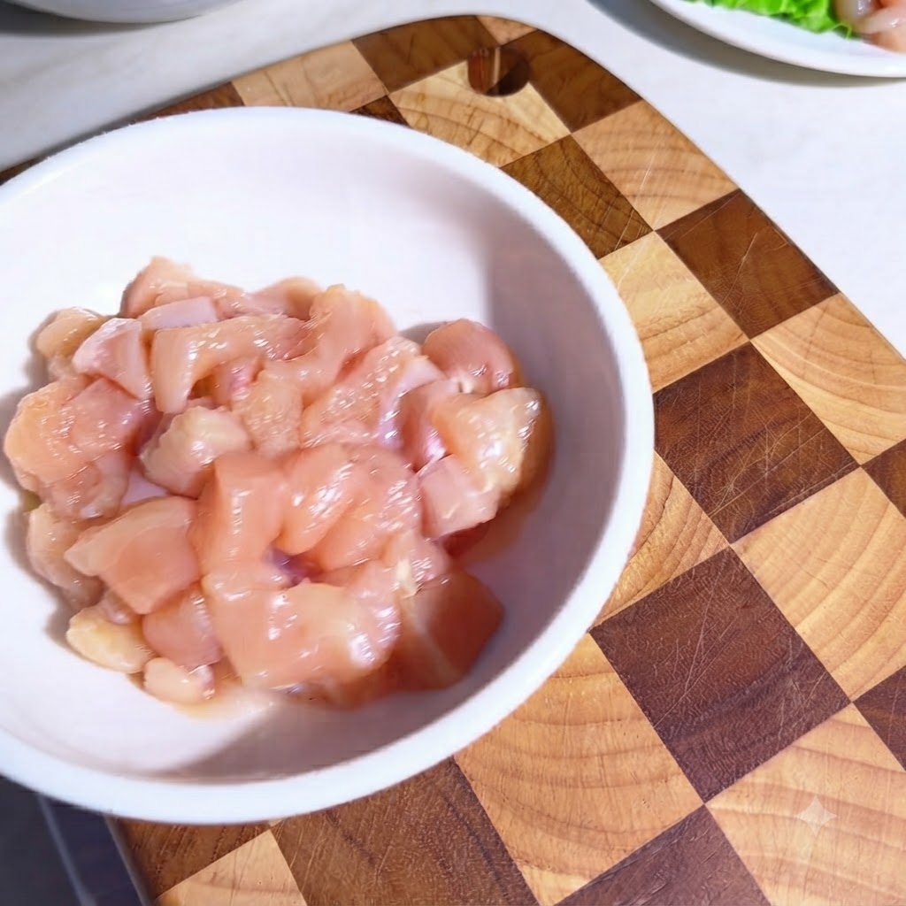 Raw chicken pieces in a white bowl coated with seasonings and olive oil.