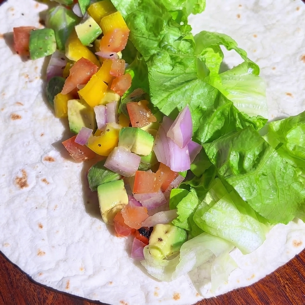 Diced cooked chicken pieces spread out over the vegetable filling on the tortilla.