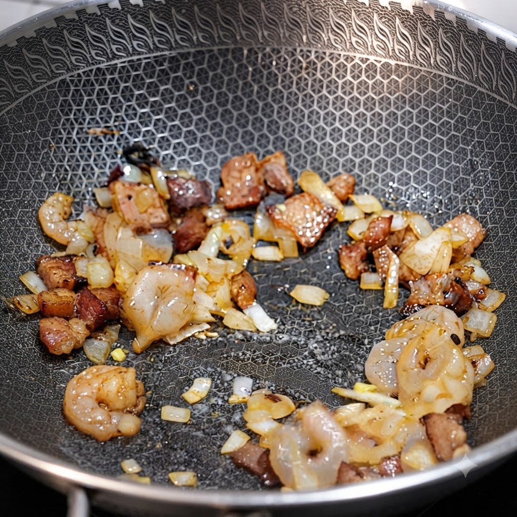 Shrimp, bacon pieces, and diced onions stir-frying together in a wok.