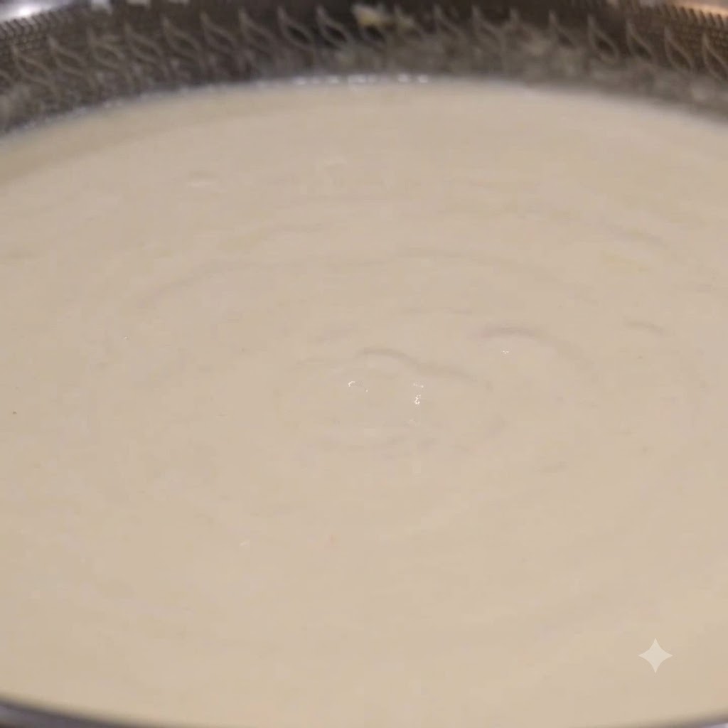 A ladle scooping creamy white clam chowder from a simmering wok.