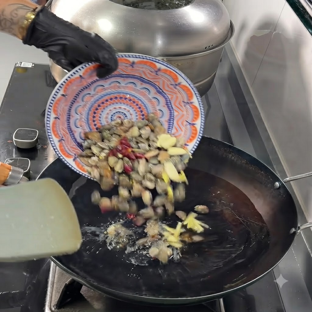 Clams, sliced garlic, ginger, and dried chili peppers falling from a plate into the hot wok.