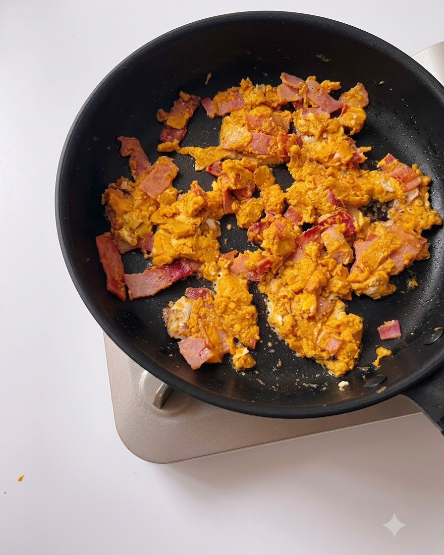 Water being poured from a measuring cup into a black pan with salted egg yolk and bacon.