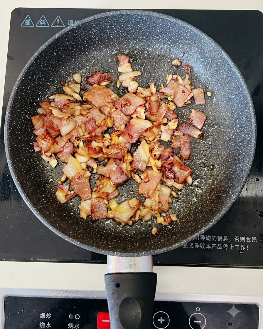 Clear water being poured from a bowl into a pan containing cooked bacon and onions.