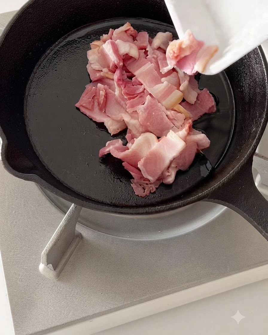 Chopped bacon pieces frying in a hot cast-iron skillet.